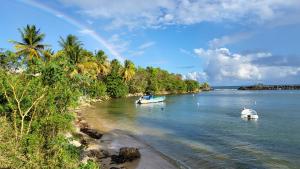 two boats in the water near a beach with a rainbow at Escale caraibe in Le Gosier