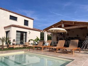 a house with a swimming pool with chairs and an umbrella at Villa Signature in Le Bosc