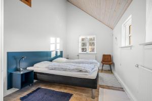 a bedroom with a bed with a blue headboard at Feriehus 1150 in Ringkøbing +31 photos