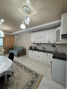 a kitchen with white cabinets and a table in a room at высотка 15 in Aktobe