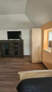 a room with a television and a dresser and a room with a bed at Moni's Ferienwohnung in Hammelburg