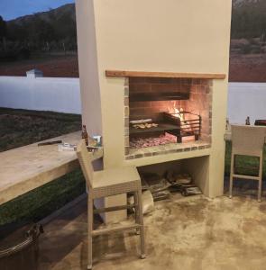 a patio with a fireplace with two chairs and a table at Windkraal Farm House in Bonnievale