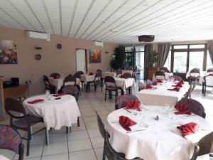 a restaurant with white tables and chairs with red napkins at Logis La Rose Des Vents in Volvic