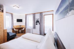 a hotel room with two beds and a desk at Pension Bavaria in Mittenwald