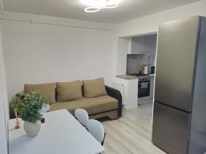 a living room with a couch and a table and a kitchen at Apartament confortabil, ideal pt 2 adulti si 2 copii sau 3 adulti in Râmnicu Vâlcea