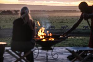 two women standing around a grill with zebras in the background at Entalet Mara Camp in Talek