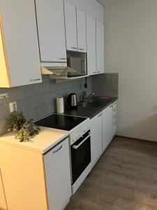 a kitchen with white cabinets and a black stove top oven at Air conditioned Apartment in Espoo +4 photos
