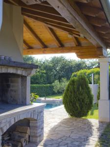 a patio with a stone fireplace and a wooden pergola at Casa Allure in Višnjan