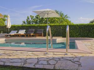 a pool with two chairs and an umbrella at Casa Allure in Višnjan