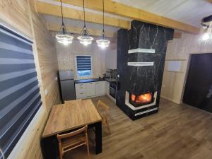 a kitchen with a wooden table and a fireplace at Domek nad jeziorem Wilczyńskim in Świętne
