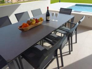 a table with a bowl of fruit and a bottle of wine at Apartman Blaženka in Kampor