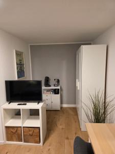 a living room with a tv and a white refrigerator at Apartment Tanne in Düsseldorf