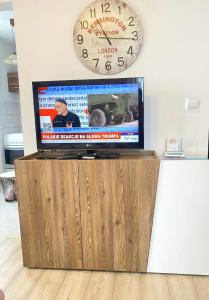 a flat screen tv on a wooden entertainment center with a clock at STARE MIASTO in Olsztyn