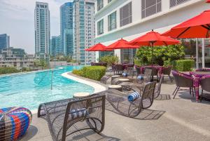 a pool with tables and chairs and red umbrellas at Novotel Executive Hotel at Rosalina Acqua Residence Mandaluyong in Manila