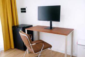 a desk with a television and a chair in a room at Travellers Palm in Ko Phangan