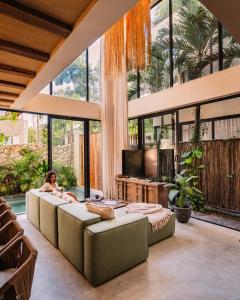 a living room with couches and a tv and large windows at Satori Tulum in Tulum