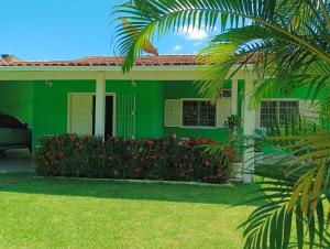 a green house with flowers in front of it at Família Castro Ostras in Rio das Ostras