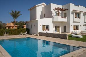 a villa with a swimming pool in front of a house at The Sandy Feet Sea Front in Hurghada