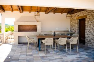 an outdoor kitchen with a wooden table and chairs at Villa Ruška in Ljubuški