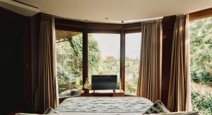 a bedroom with a bed and a large window at Dacolina House Jimbaran in Jimbaran