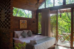 a bedroom with a bed in a brick wall at Heaven's Acres Lodge - Private one Bedroom Cabana in Matale