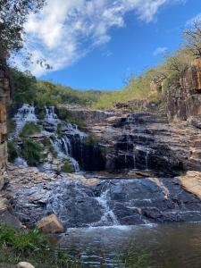 a waterfall on the side of a rocky river at Pousada e Pesqueiro Recanto do Peixe in Carmo do Rio Claro