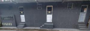 a black brick building with white windows and stairs at Jandira Hosting Acomodação in Jandira