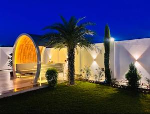a house with a palm tree in the yard at night at Vasudeva Villas in Udaipur