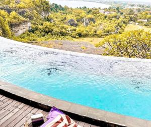 a swimming pool on a deck next to a body of water at Dacolina House Jimbaran in Jimbaran