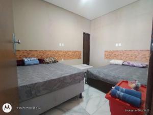a bedroom with two beds and a red suitcase at Espaço Acácia in Petrolina +24 photos