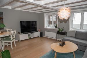 a living room with a couch and a tv and a table at Classic Stavanger Townhouse, Garden, Spacious in Stavanger