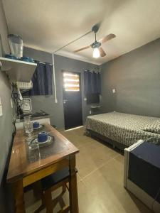 a bedroom with a bed and a table and a ceiling fan at kit net central 2 in Serra Negra