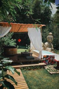 a gazebo with a buddha statue in a garden at Ônibus Oriental com Ofurô - Domingos Martins ES in Domingos Martins
