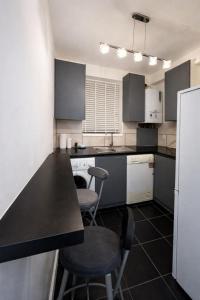 a kitchen with a black counter and two stools at Midnight Horizon - shared bathroom in Ponders End +4 photos