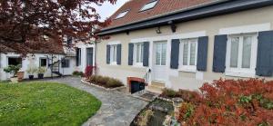 a house with blue shutters and a yard at Maison Monéteau 6 personnes in Monéteau