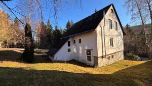 an old white building with a black roof at Chalupa U lesa in Karlova Studánka