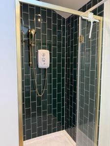 a bathroom with a shower with a green tiled wall at The Brambles bungalow in Weston-super-Mare