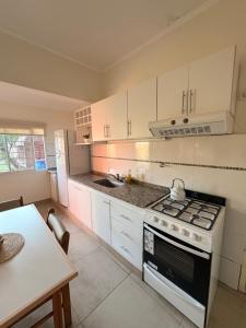 a kitchen with white cabinets and a stove and a table at Lo de Mingo in San Pedro