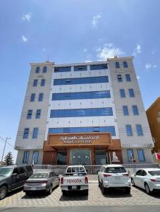 a large building with cars parked in a parking lot at اجنحة سبات الفندقيه in Ahad Rafidah