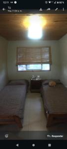 a room with two beds and a window with a window at Cabaña Flor Serrana in Tanti