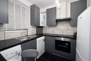 a black and white kitchen with a sink and a dishwasher at Midnight Horizon - shared bathroom in Ponders End