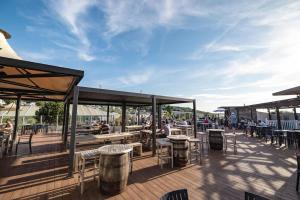 a deck with tables and chairs and people sitting at tables at Reeva's Resort at Littlesea Holiday Park, Weymouth in Wyke Regis