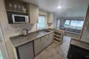 a small kitchen with a sink and a microwave at Reeva's Resort at Littlesea Holiday Park, Weymouth in Wyke Regis