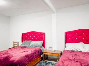 a bedroom with two beds with red covers and a table at Ruby Grey Suite in Mineral de Angangueo