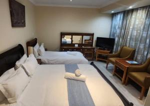 a hotel room with two beds and a television at Orchids Lodge in Fourways