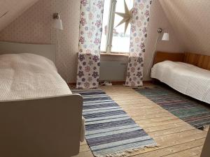 a bedroom with two beds and a window and a rug at Askebo Norregård in Askebo