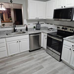 a kitchen with white cabinets and black appliances at Convenient 3 bedroom Townhome in Raleigh +10 photos