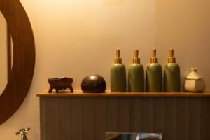 a shelf with three green bottles and a cat statue at The Oneness Living- Seasonal Heritage stay with Tholpaavakoothu nights in Pazhayannūr +26 photos