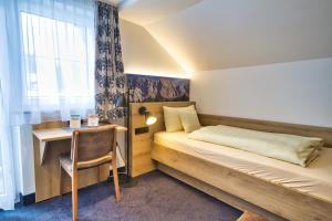 a bedroom with a bed and a desk and a window at Zum Franziskaner in Grainau