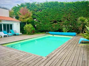 a swimming pool on a wooden deck with blue chairs at Maison Aquitaine "Tanchet" in Les Sables-d'Olonne +20 photos